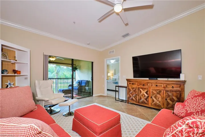 Living area with a ceiling fan, crown molding, and tile patterned floors
