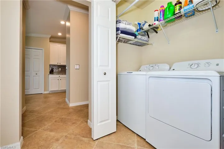 Laundry room featuring washer and clothes dryer, crown molding, light tile patterned flooring, and recessed lighting
