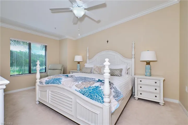 Bedroom with light carpet, ornamental molding, and ceiling fan