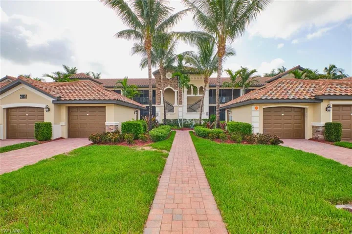 View of front of home with stucco siding, a front yard, stone siding, a tile roof, and driveway