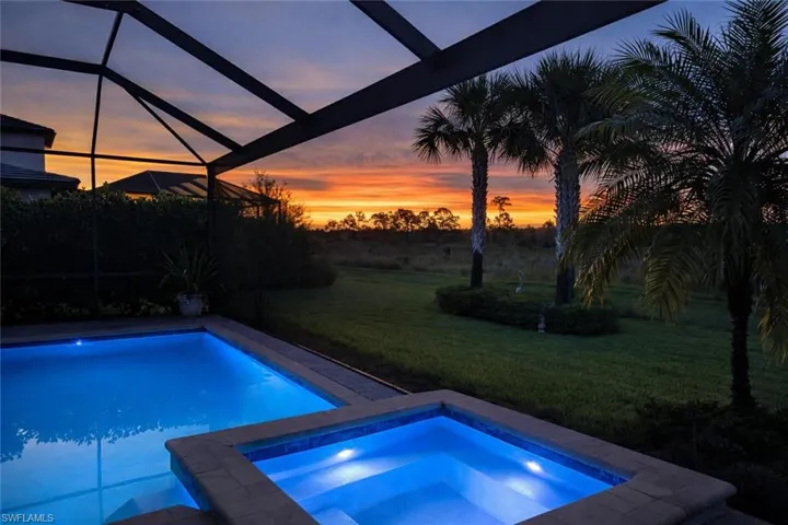 Pool at dusk featuring an in-ground hot tub, a lanai, an outdoor pool, and a patio area