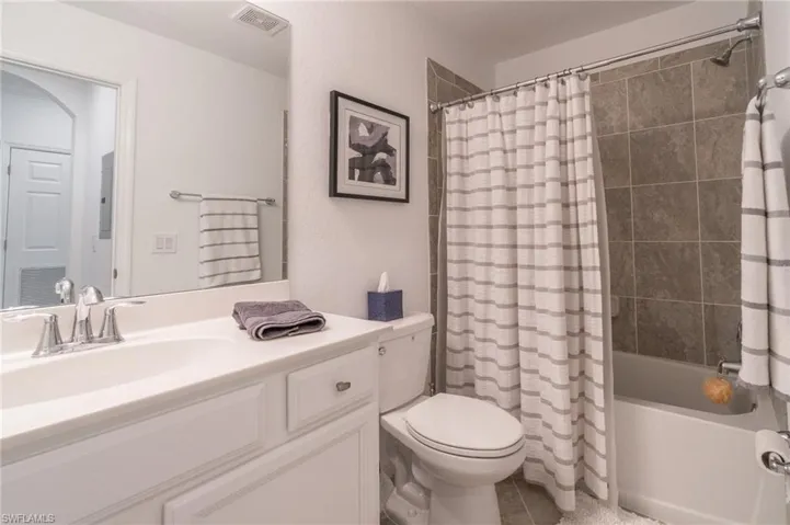Full bathroom featuring shower / bath combo with shower curtain, tile patterned floors, toilet, and vanity