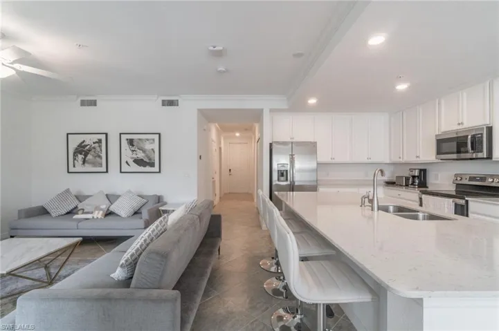 Kitchen featuring sink, dark tile patterned floors, a breakfast bar area, and stainless steel appliances