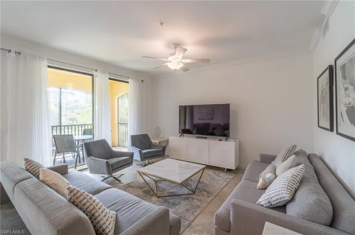 Tiled living room featuring ornamental molding and ceiling fan