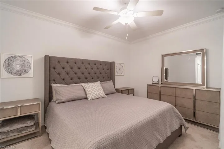Bedroom with crown molding, ceiling fan, and light colored carpet