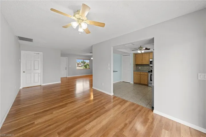 Unfurnished living room with ceiling fan, a textured ceiling, and light wood-style flooring