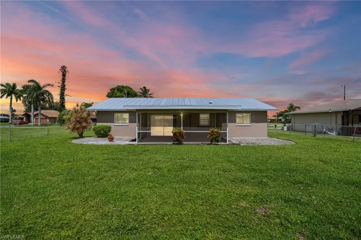 Back of property featuring a sunroom, a metal roof, and stucco siding