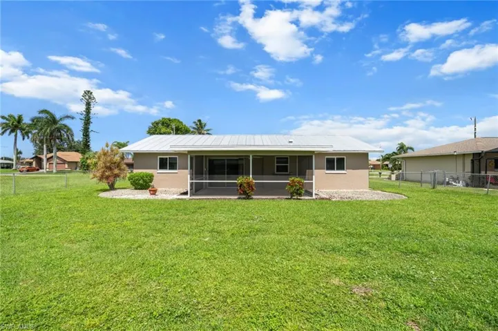 Back of house with a sunroom, a metal roof, stucco siding, and a fenced backyard