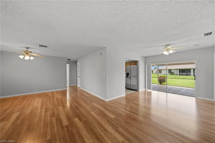 Unfurnished living room with ceiling fan, a textured ceiling, and light wood finished floors