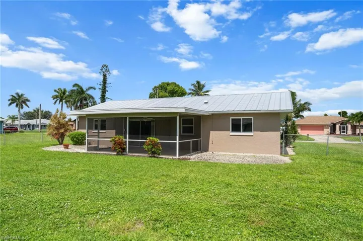 Rear view of property with stucco siding, a sunroom, and a metal roof