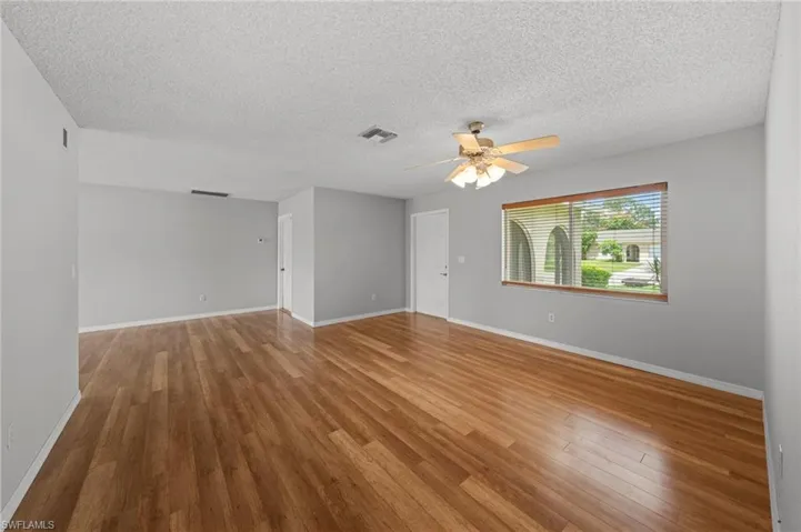 Unfurnished room featuring a ceiling fan, a textured ceiling, and wood finished floors