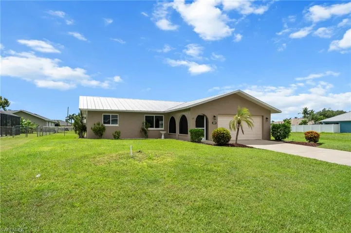 Single story home featuring stucco siding, an attached garage, concrete driveway, and a metal roof
