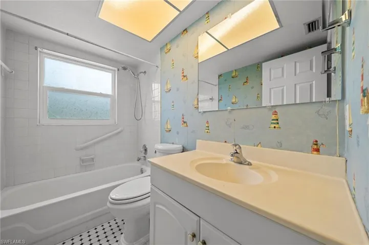 Bathroom featuring vanity,  shower combination, and wallpapered walls