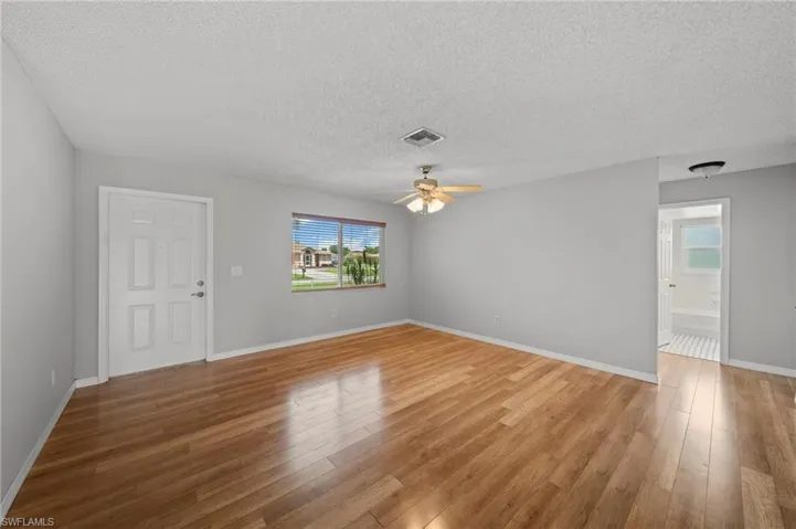 Unfurnished room featuring a textured ceiling, light wood finished floors, and a ceiling fan