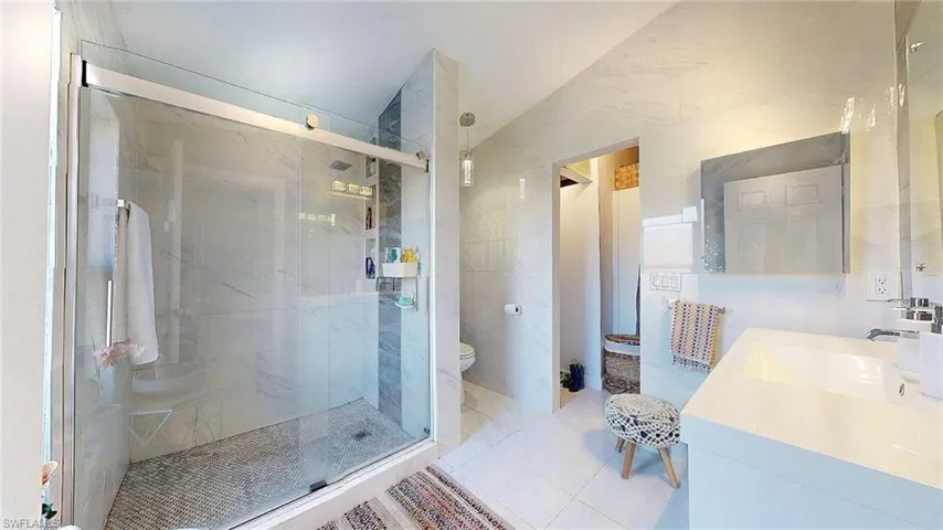 Full bath with a shower stall, vanity, light tile patterned flooring, and tile walls