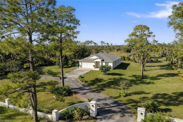 View of front facade with driveway, an attached garage, a front yard, and a view of rural / pastoral area
