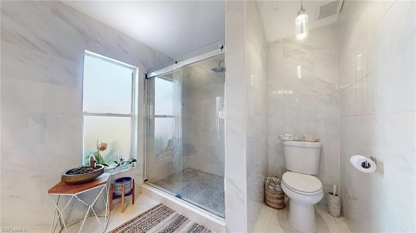 Full bathroom featuring tile walls, a stall shower, and tile patterned floors