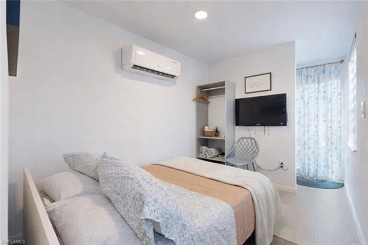 Bedroom with an AC wall unit and wood finished floors