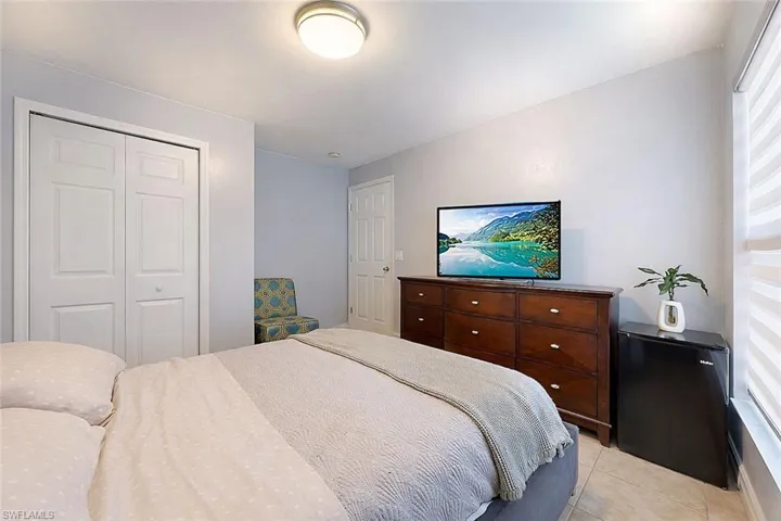 Bedroom with a closet, light tile patterned flooring, and black refrigerator