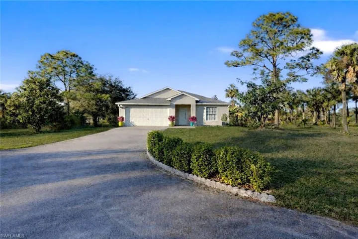 Single story home featuring a front yard, asphalt driveway, a garage, and stucco siding