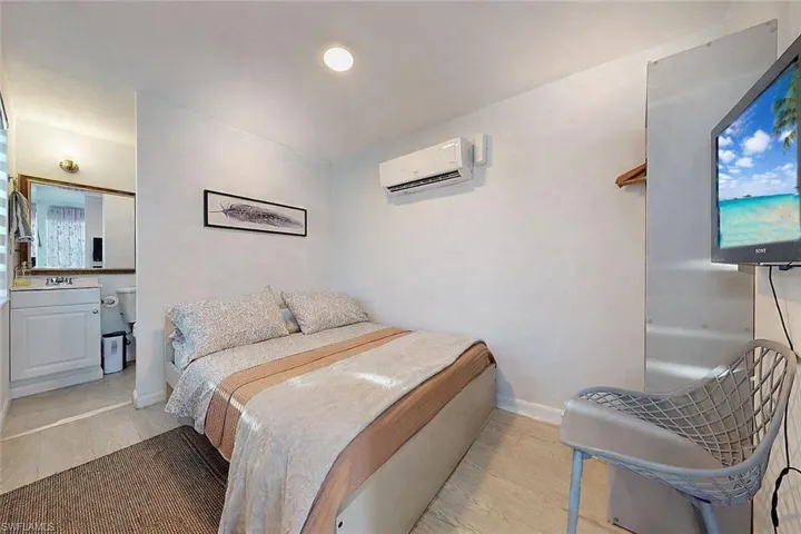 Bedroom featuring light wood finished floors, a wall mounted AC, and ensuite bathroom
