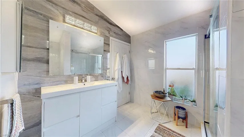 Bathroom with a stall shower, tile walls, vanity, and light tile patterned floors