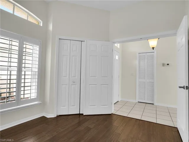 Den (or office/3rd bedroom) with hardwood floors, a towering ceiling, and a closet