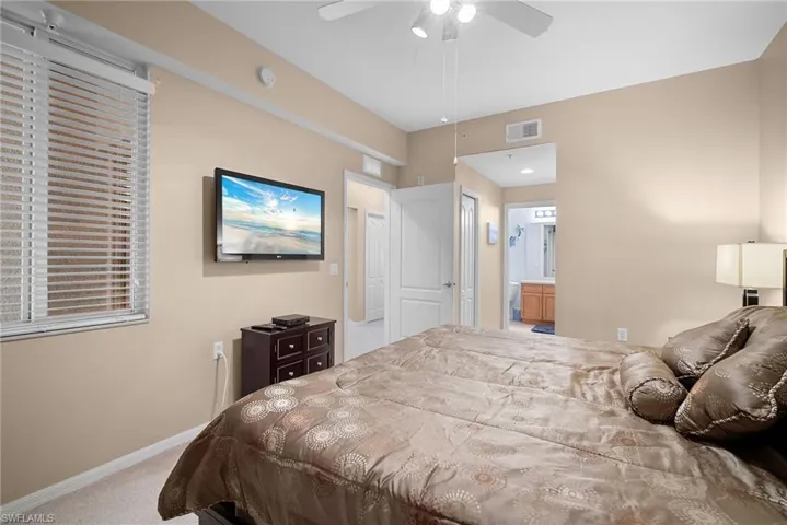 Bedroom featuring light colored carpet, a ceiling fan, and ensuite bathroom