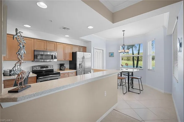 Kitchen featuring crown molding, appliances with stainless steel finishes, light tile patterned floors, a peninsula, and hanging light fixtures