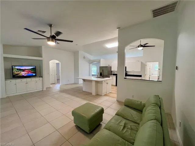 Living room with ceiling fan, sink, and light tile floors