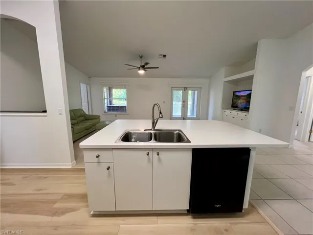 Kitchen featuring white cabinetry, sink, dishwasher, and a kitchen island with sink