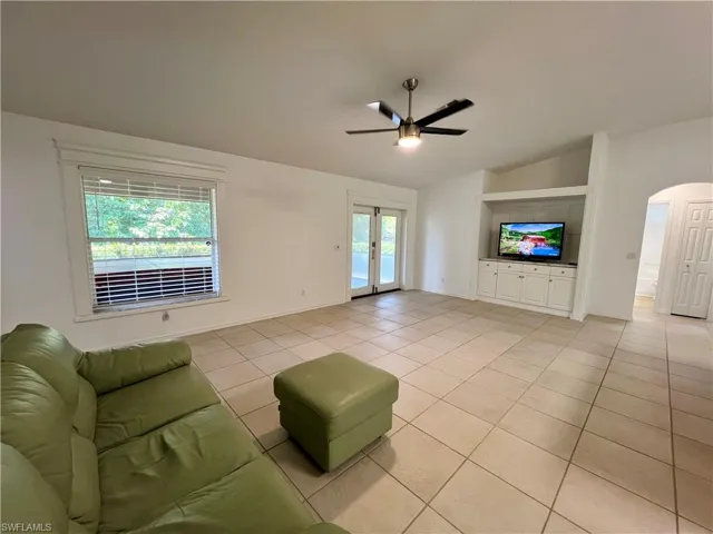 Tiled living room featuring ceiling fan and french doors