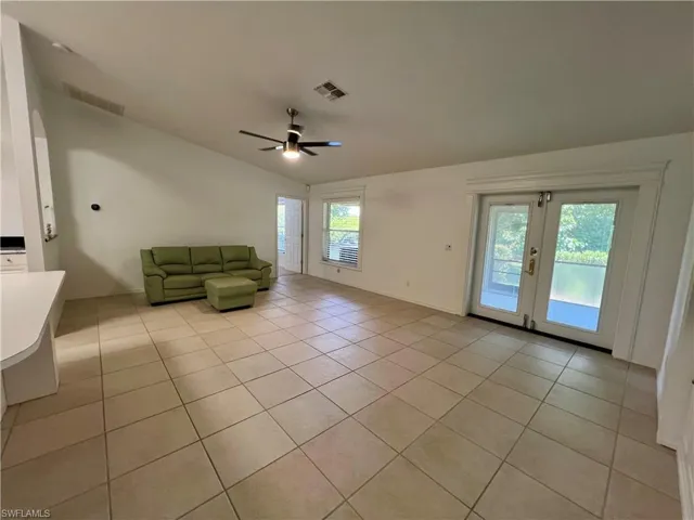 Unfurnished living room featuring plenty of natural light, ceiling fan, french doors, and vaulted ceiling