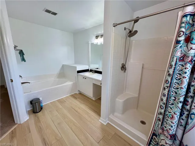 Master Bathroom with  wood-style plank flooring, separate shower and tub, and oversized vanity