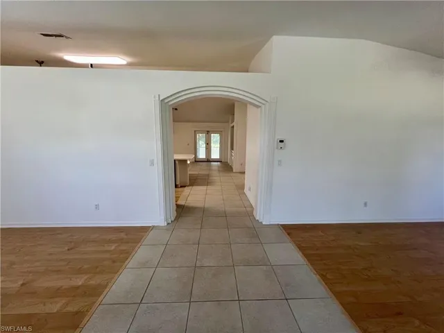 Entry foyer with triple arch featuring vaulted ceiling and light tile floors