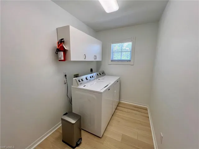 Laundry room featuring cabinets, hookup for an electric dryer, light hardwood / wood-style floors, and washer and clothes dryer