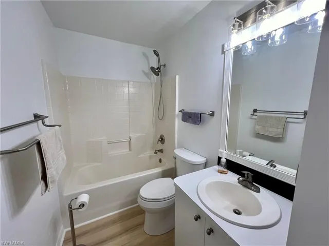 Full guest bathroom with  shower combination, vanity, toilet, and wood-type flooring