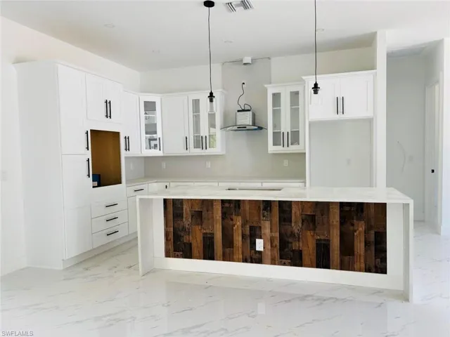 Kitchen featuring glass insert cabinets, a kitchen island, marble finish floor, and white cabinets