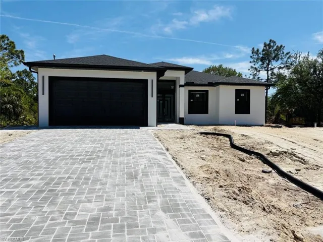 View of front of house with stucco siding, decorative driveway, a garage, and a shingled roof