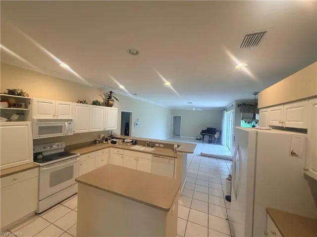 The kitchen features white cabinetry, a white refrigerator, and an electric range, with light-colored countertops