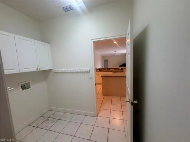 Dedicated laundry area featuring white cabinetry, a utility hookup, and tiled flooring