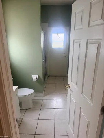 Bathroom with light green walls and white tiled flooring