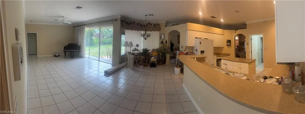 Expansive living area featuring tile flooring, a ceiling fan, and sliding glass doors that open to the outdoor space