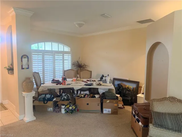 This room features an arched window with plantation shutters, crown molding, and an arched entryway
