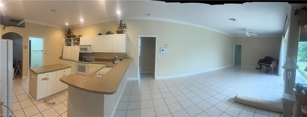 The property features a kitchen with white cabinetry, an island, and a breakfast bar