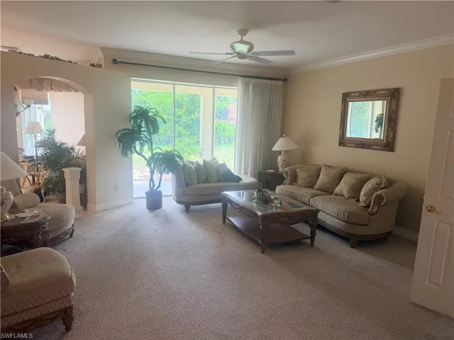 The living area features a neutral color palette, an arched entryway, and a ceiling fan