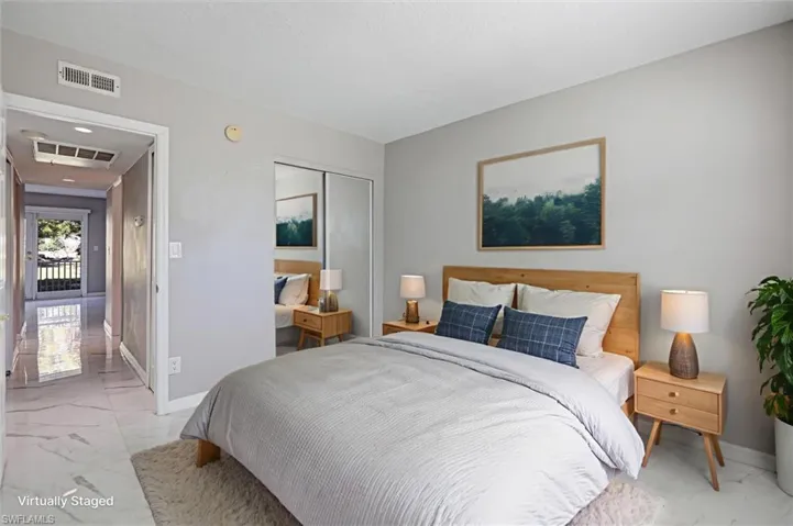Virtually staged Bedroom with light marble finish flooring and a mirrored closet door