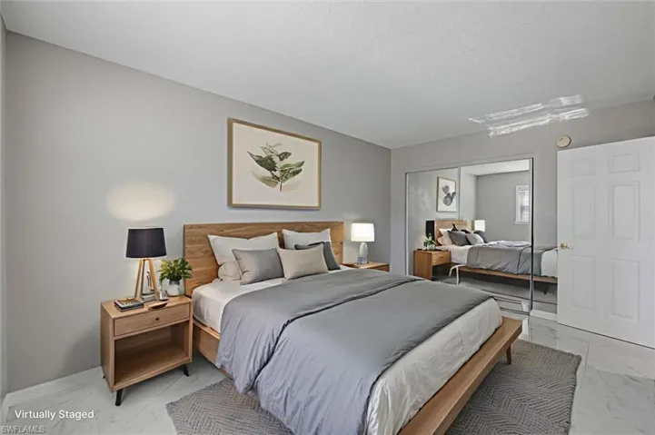 Virtually staged Bedroom featuring marble finish floors and a mirrored closet