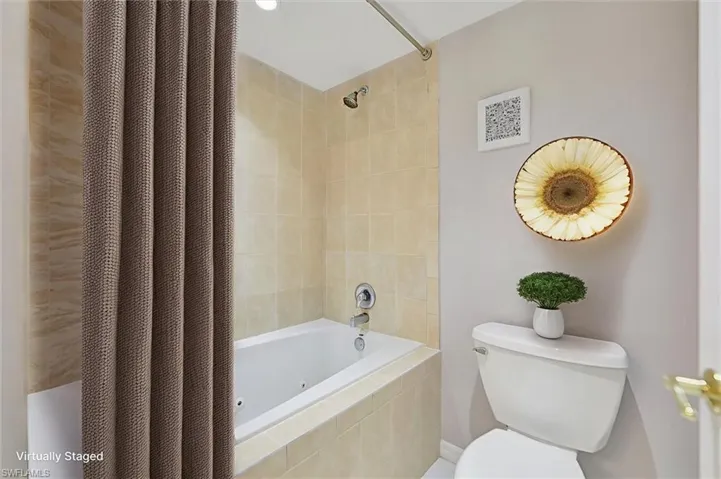 Virtually staged Full bathroom with a combined bath / shower with jetted tub and toilet