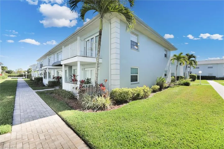 View of property exterior featuring stucco siding, a lawn, and a balcony